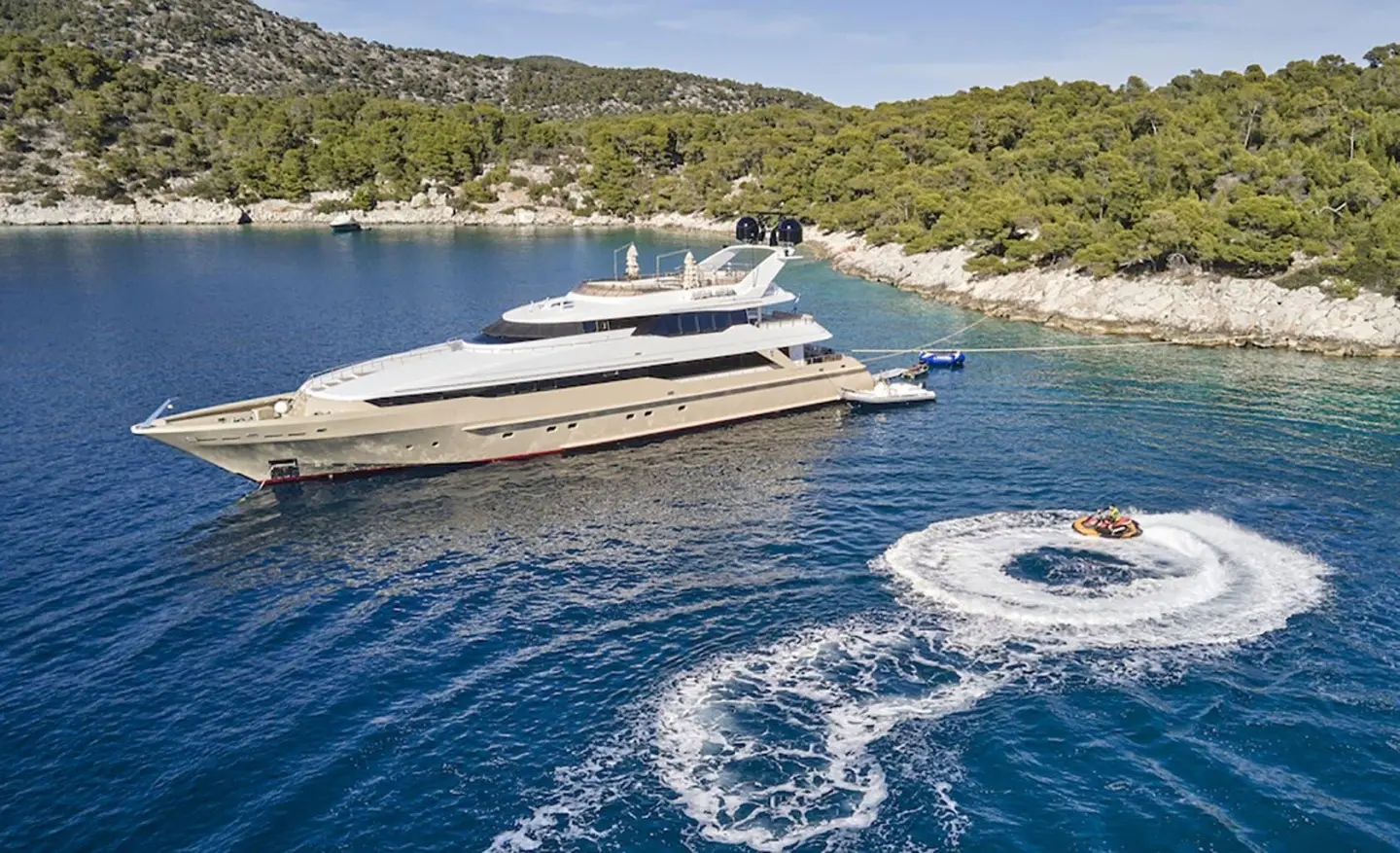 Daloli motor yacht anchored near rocky coastline with clear blue water