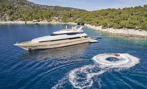 Daloli luxury motor yacht anchored near a forested rocky coastline with clear blue water