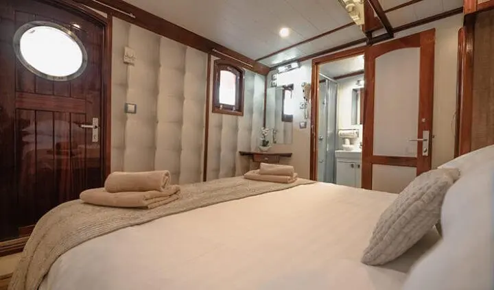 Master cabin with king bed, wood paneling, ensuite likely, warm lighting
