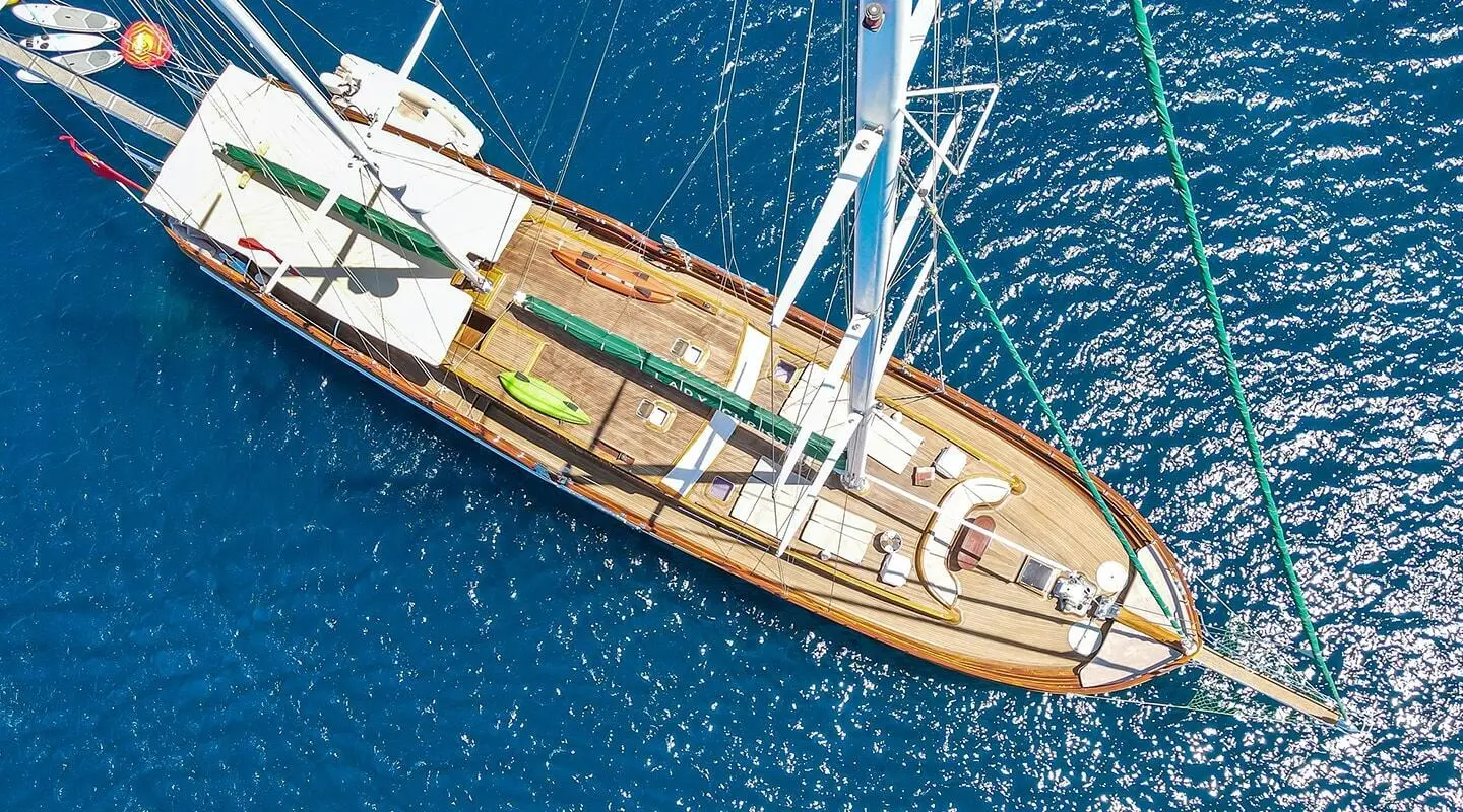 Wooden gulet sailing yacht on blue sea, aerial view with sails and deck