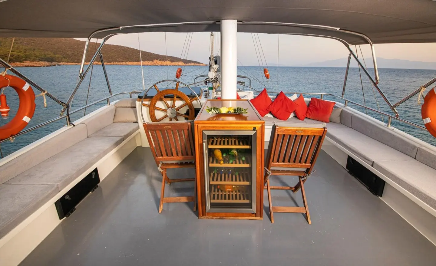 On deck of Bodrum Queen gulet, wooden chairs facing sea, warm sun, charts and bar in view