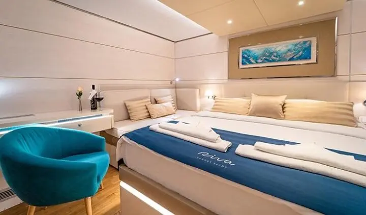 Riva yacht cabin with king bed, wood panels, blue accents, and ensuite.