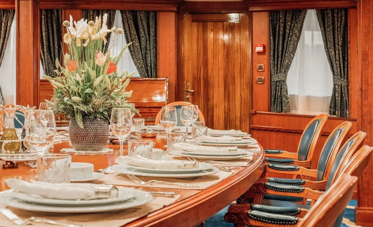 Seagull II dining room aboard wooden yacht, round table set with glassware