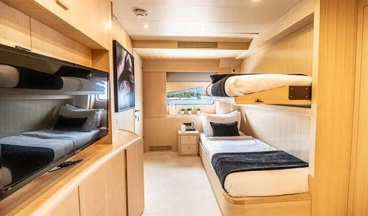 Cozy cabin bunk area on Pareaki II yacht, wood finishes and compact beds