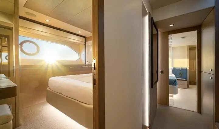 View of a yacht cabin with a king bed, wood paneling, and soft lighting