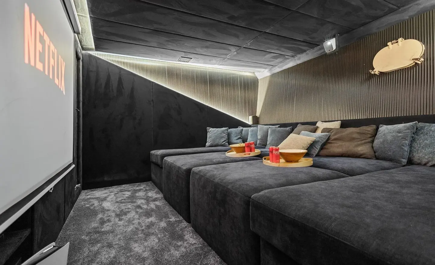 Cozy indoor lounge with dark gray sectional seating and round trays with Coca-Cola cans