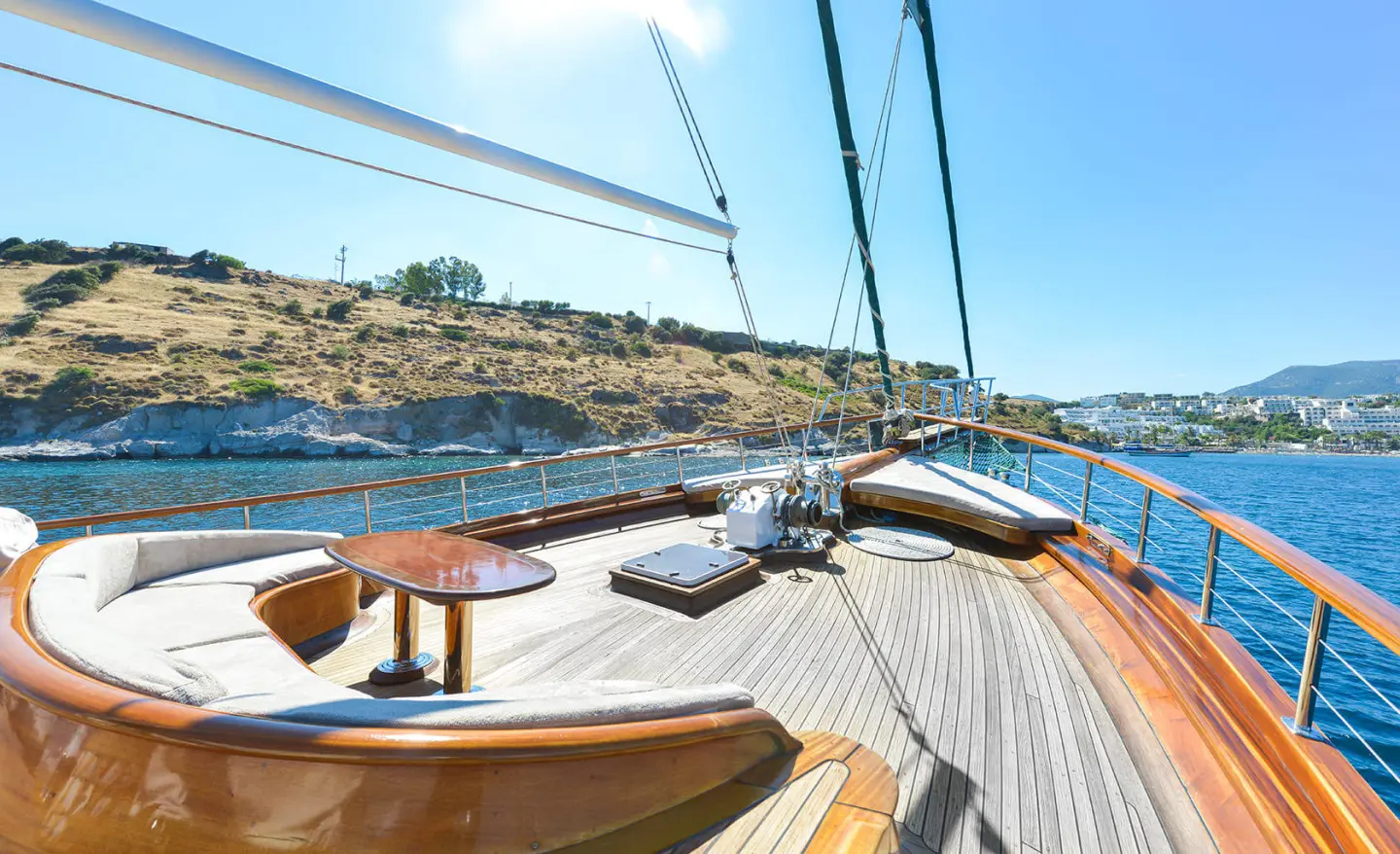 View from yacht deck at sunset with wooden deck, rigging, and sea horizon