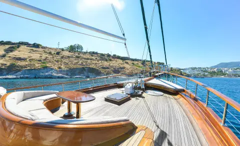 View from yacht deck at sunset with wooden deck, rigging, and sea horizon