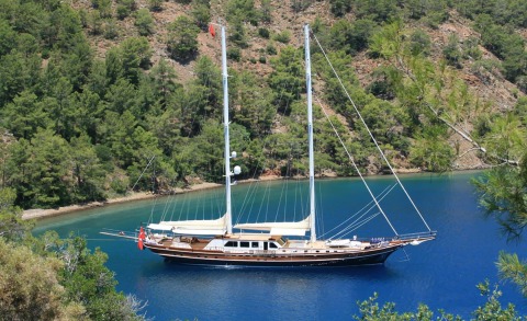 Kaya Guneri 5 sailboat anchored in a serene turquoise cove among pine-covered cliffs