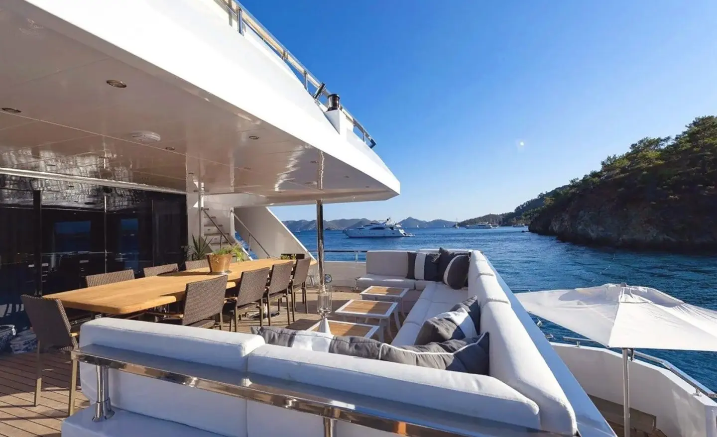 Ocean Breeze yacht deck aboard, sun loungers and seating along railing on calm blue sea