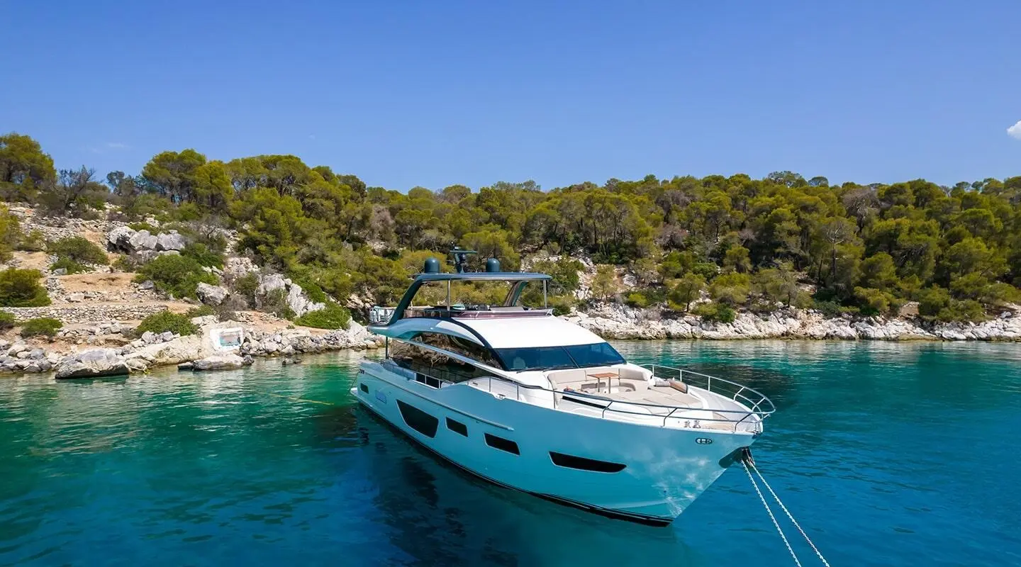 Vista yacht anchored beside a rocky coastline with clear blue water