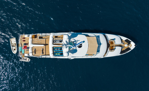 Aerial view of a large luxury yacht on blue sea, its upper deck and equipment visible