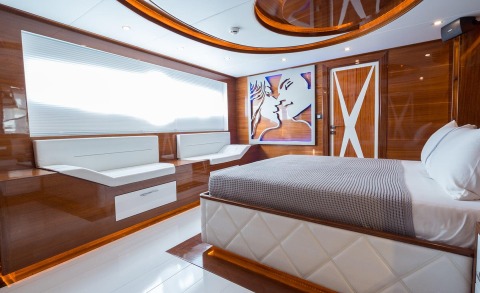 Luxurious wood-paneled bedroom on yacht with large bed and seating area