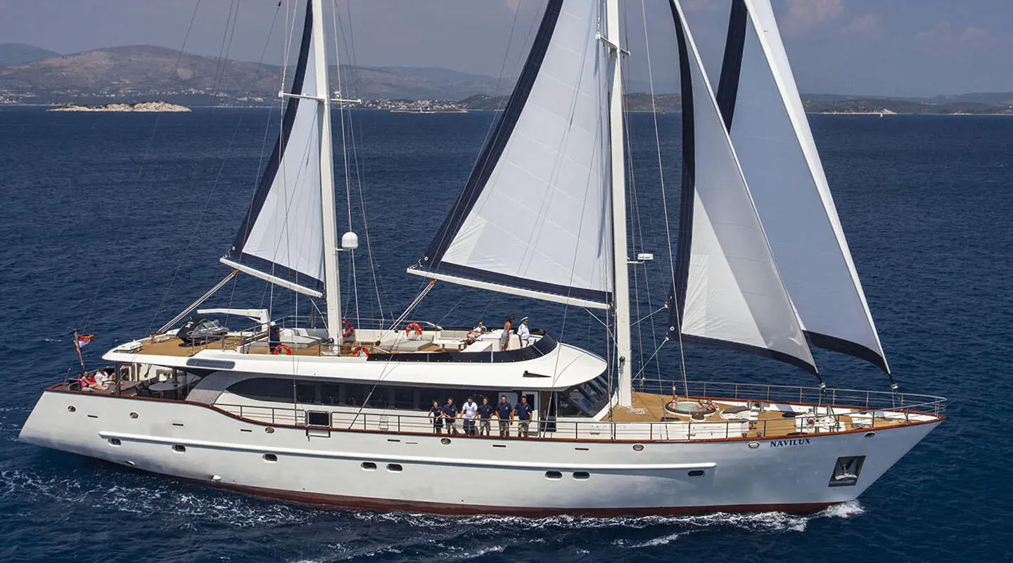 Navilux sailing yacht on blue water with white sails raised and crew onboard