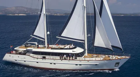 Navilux sailing yacht on blue water with white sails raised and crew onboard