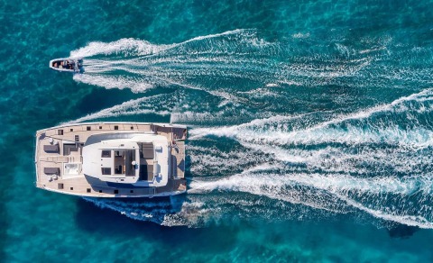 Aerial view of a large yacht on blue waters with a small speedboat nearby