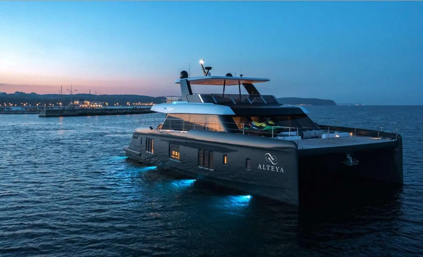 Alteya yacht anchored at sunset, dark blue water reflects the hull and sky