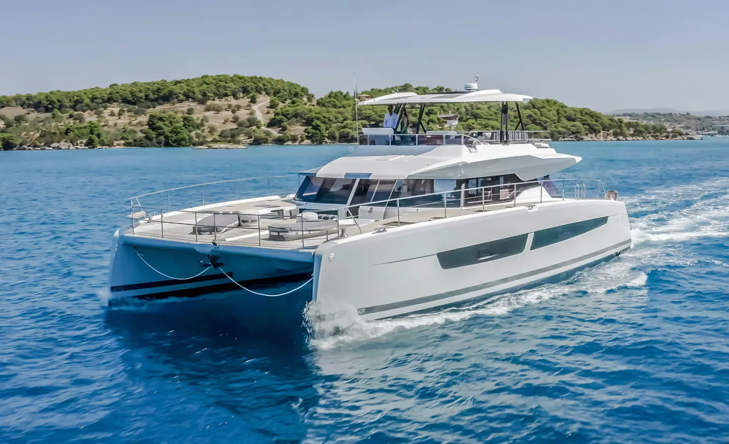 Luxury D2 yacht sailing waterside with clear blue sea and rocky shore