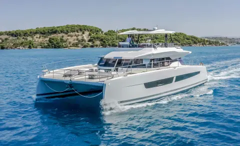 Luxury D2 yacht sailing waterside with clear blue sea and rocky shore