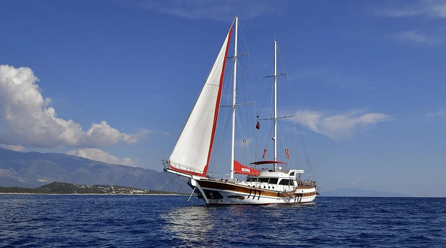 Blu Dream sailing yacht with white hull, red boat, and sails on calm blue sea