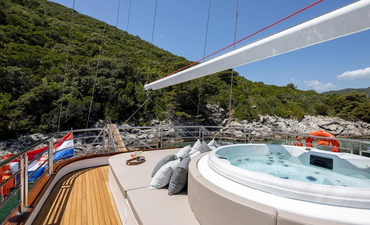 Love Story yacht with sunlit deck, hot tub, and sailing rig at sunset