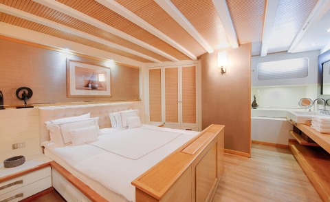 Double bed in Cobra King yacht cabin with wooden interior and white bedding