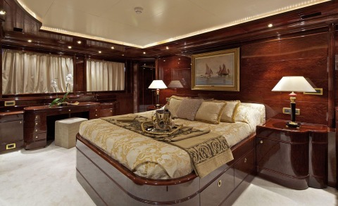 Luxury yacht bedroom with wood paneling, artwork and lamps
