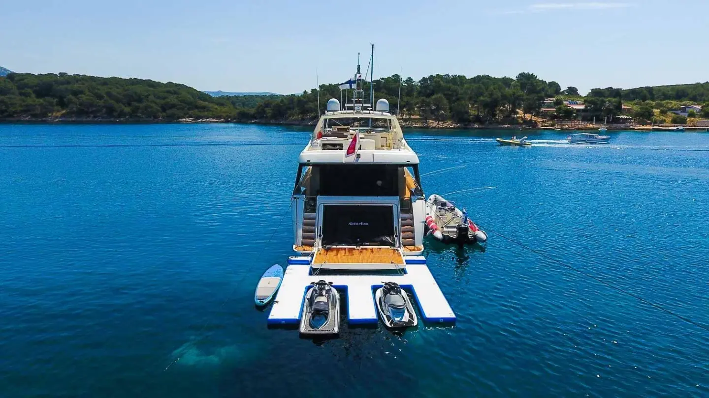 A luxury yacht named Miss Katariina anchored in calm blue water near shore