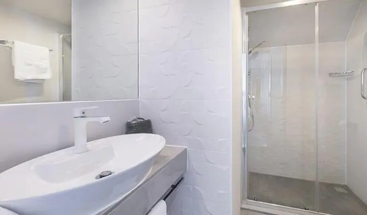Yacht cabin bathroom with sink, mirror, and shower door visible