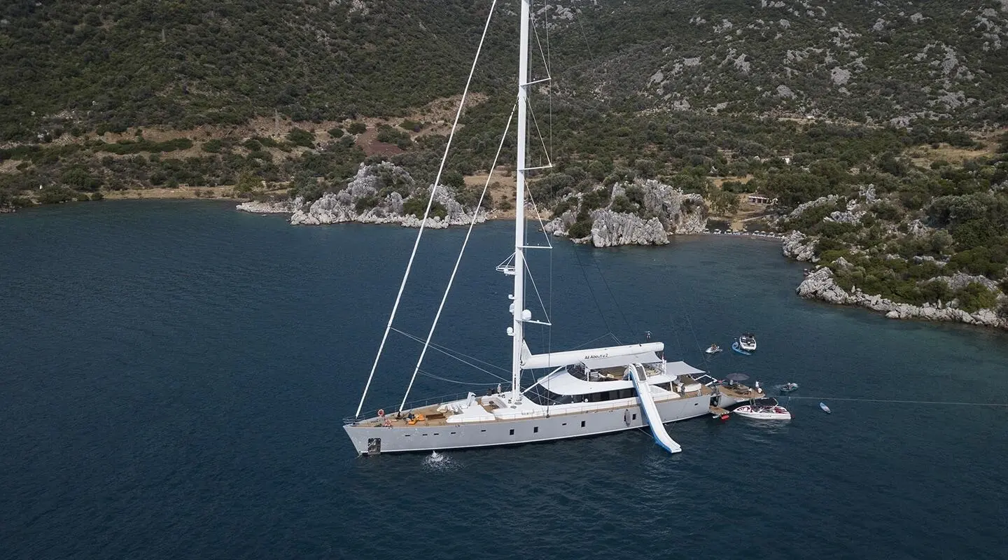 Aerial view of a white sailboat with a mast on a blue sea
