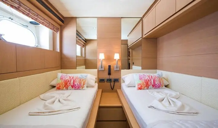 Twin-cabin ensuite yacht interior with two neatly made beds and wooden cabinetry