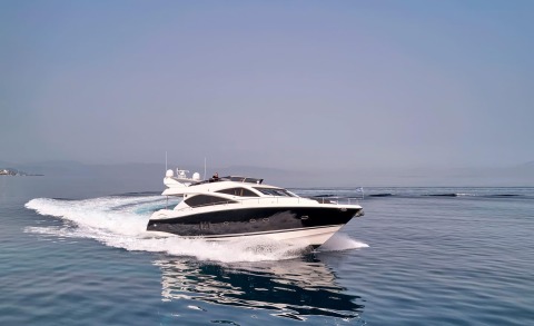 M Five yacht speeding on the water, white and black luxury motorboat with blue sky and distant shore