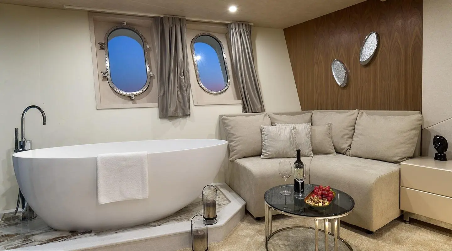 Luxurious yacht cabin interior with cream seating, wood paneling, and round porthole windows
