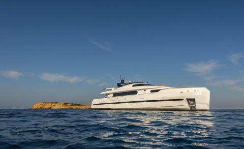 Project Steel luxury motor yacht gliding on blue sea near rocky coastline