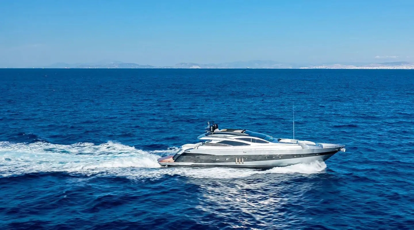 Luxury motor yacht cruising on calm blue sea at sunset with wake trailing