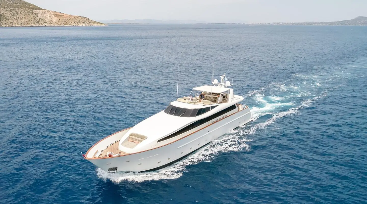 White luxury motor yacht cruising on open sea with wake behind it