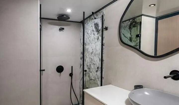 Calm Down yacht cabin bathroom with glass shower, round mirror, and modern fixtures