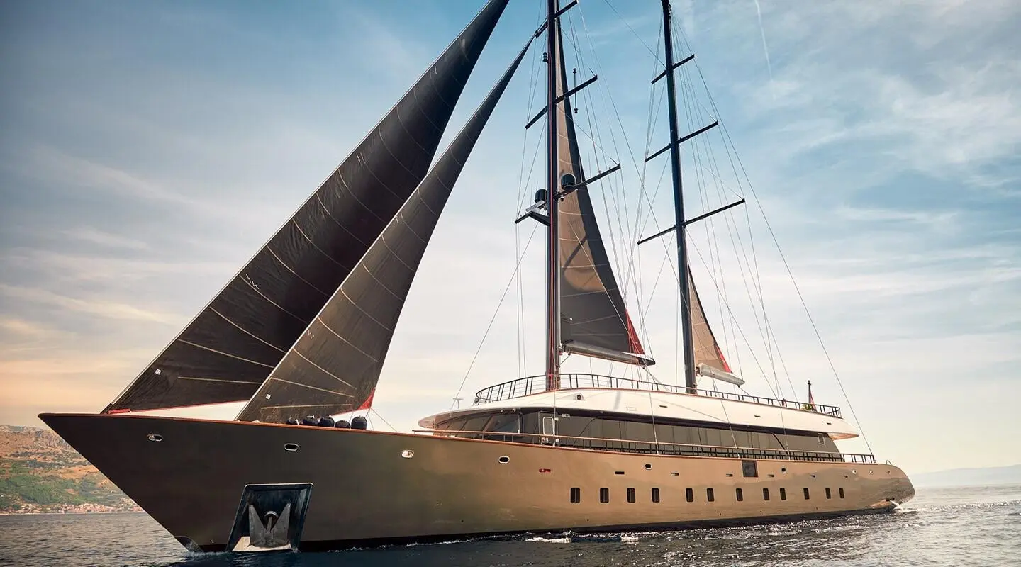 Anetta luxury motor yacht with sails raised, sleek hull, mast, and clear blue sky