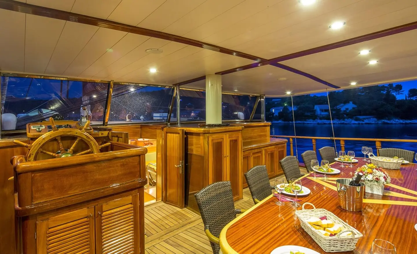 Morning Star yacht interior with wooden dining area and curved seating at night