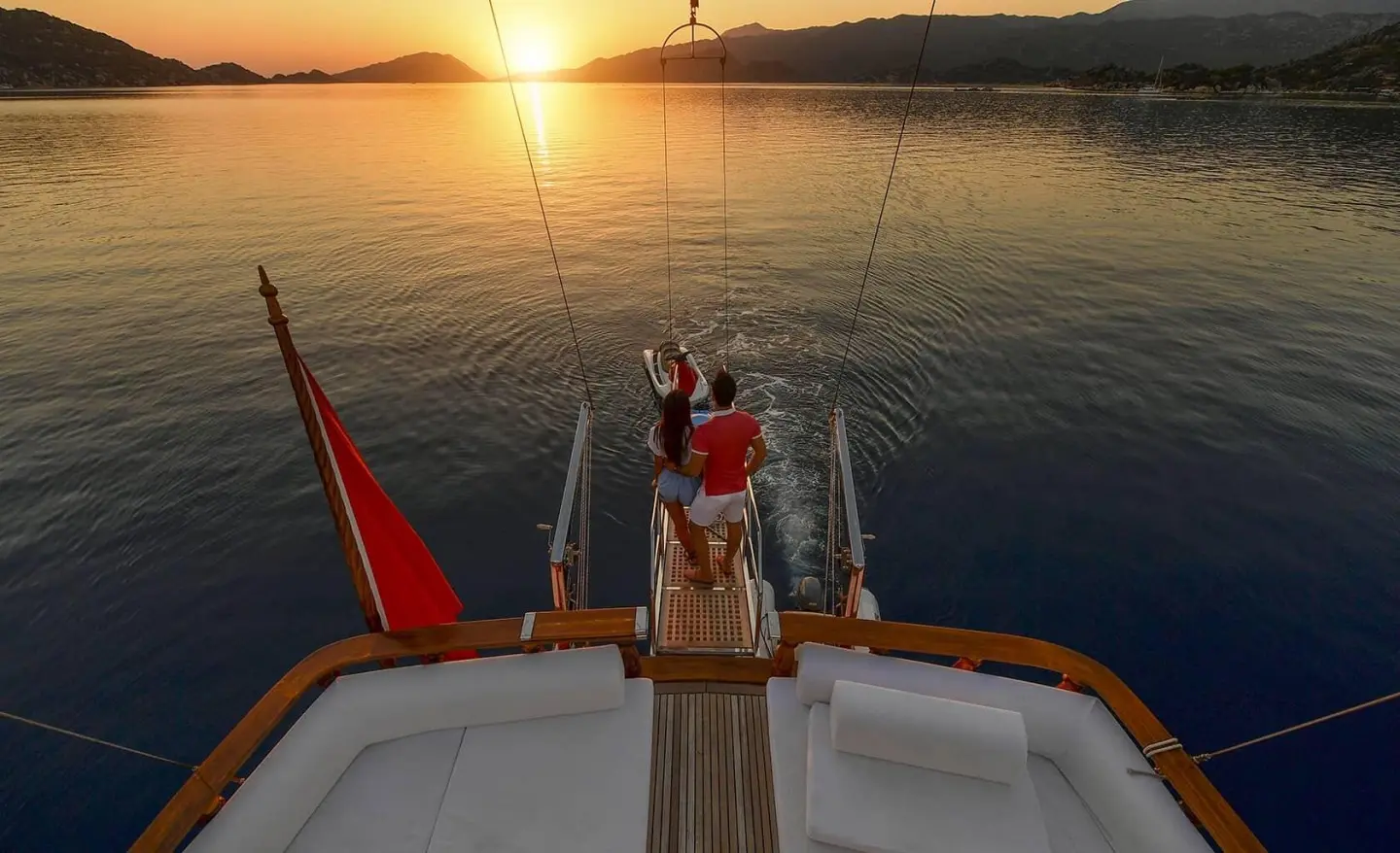 Blu Dream yacht deck at sunset with two people standing near rail, calm sea