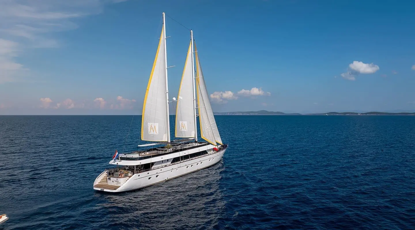 Two-masted white sailing yacht cruising on blue sea