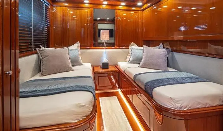 Luxurious yacht cabin interior with twin beds, seating, wood paneling, and soft lighting