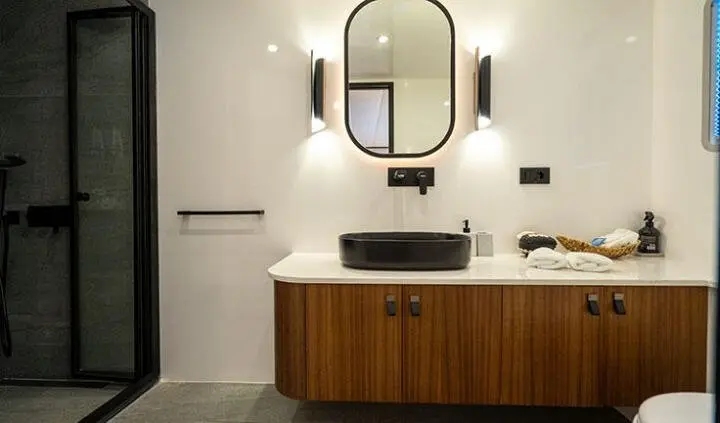 Master cabin with king bed, ensuite vanity, round mirror, and wooden cabinet