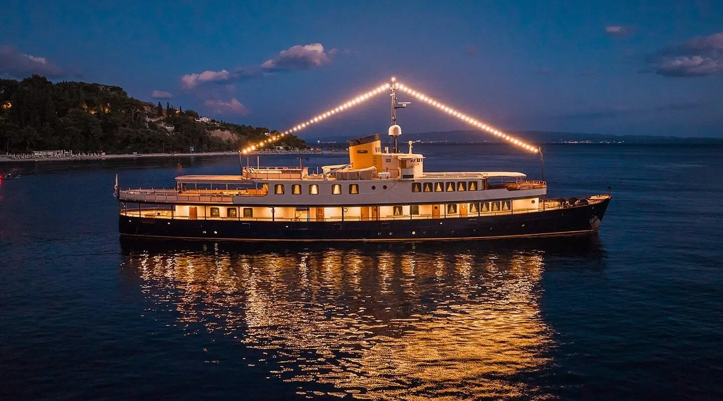Seagull II yacht docked at night with lit building reflections on calm water