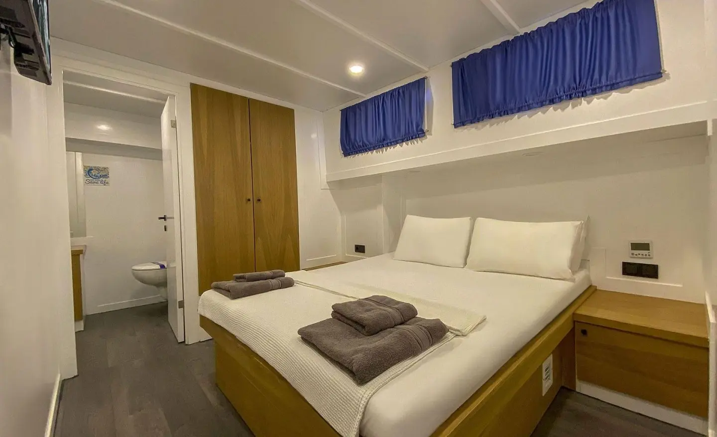 Maske 5 yacht interior: bright cabin with large bed, pillows, wooden accents