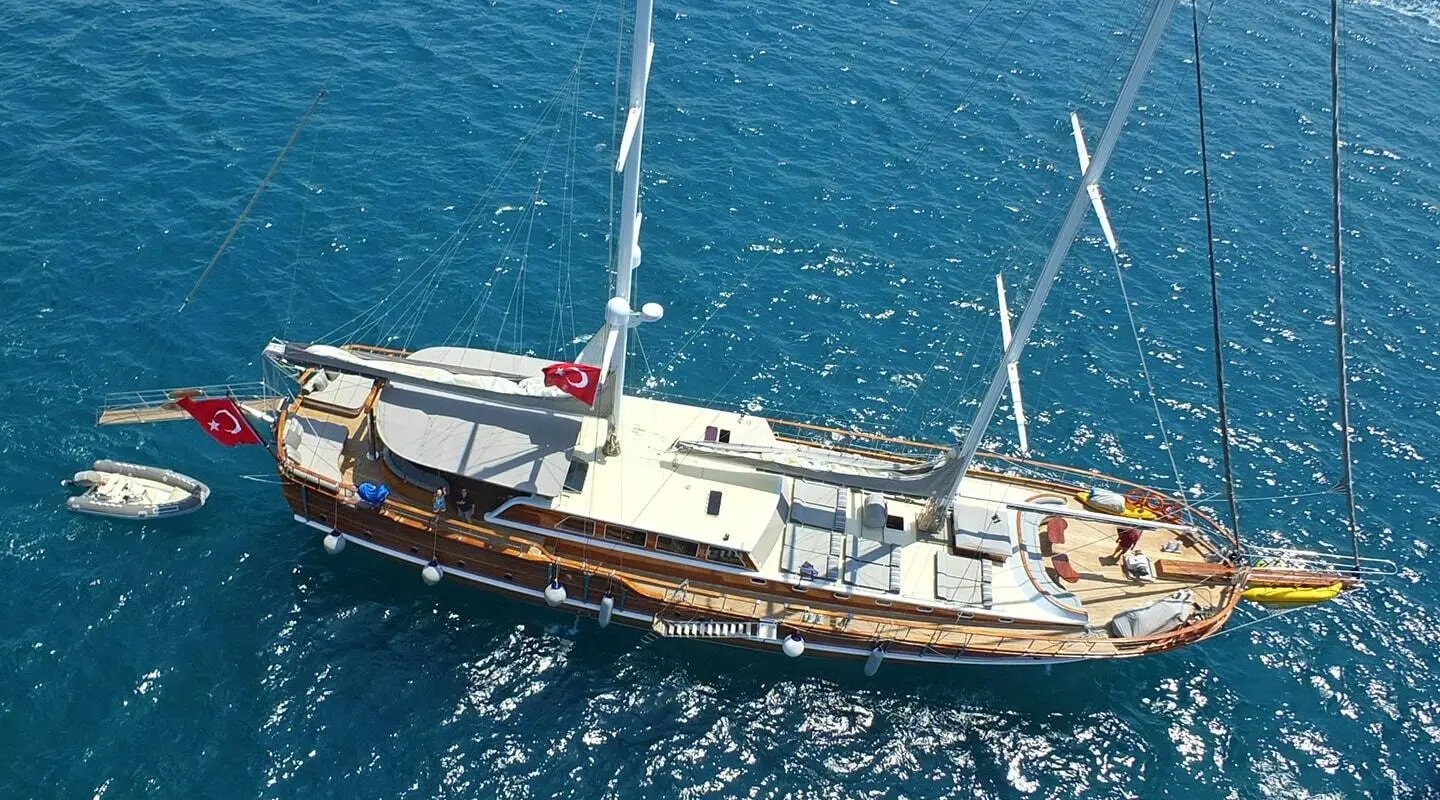 Small luxury gulet yacht named Kaptan Mehmet Bugra anchored in blue sea at sunset