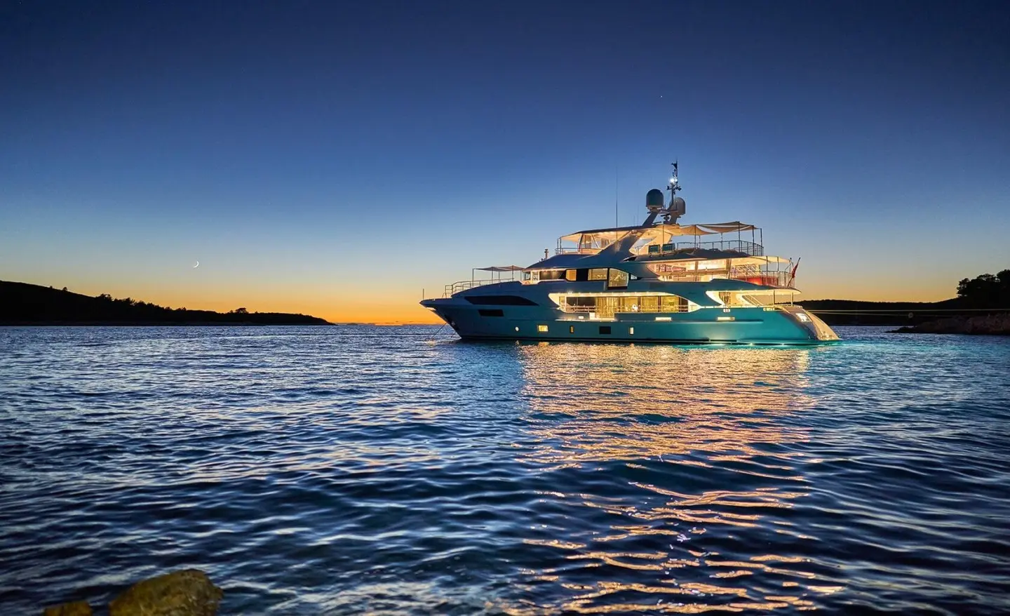 Happy Me yacht anchored on calm water at sunset with a dark blue sky