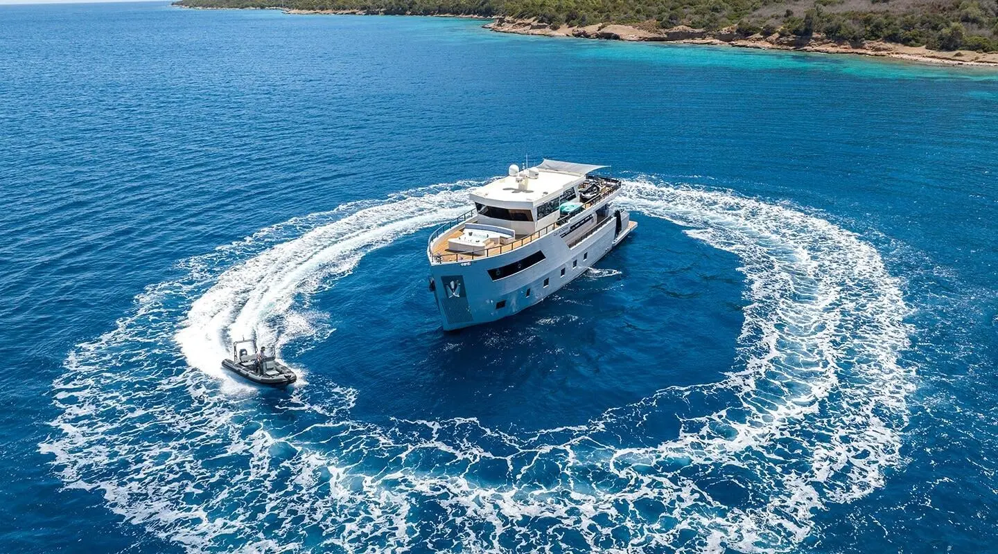 Calm Down yacht sails through blue Caribbean waters near a rocky coastline