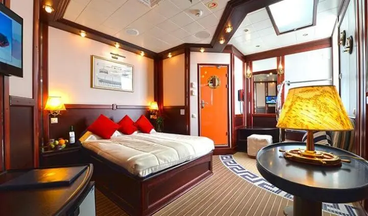 Interior of a yacht cabin with a double bed and red pillows, wooden accents