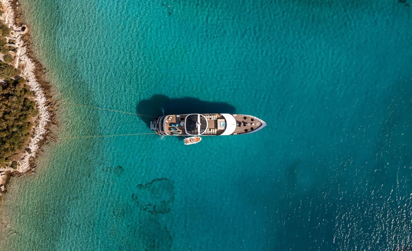 Aerial view of a sleek motor yacht named Karizma anchored in clear turquoise water